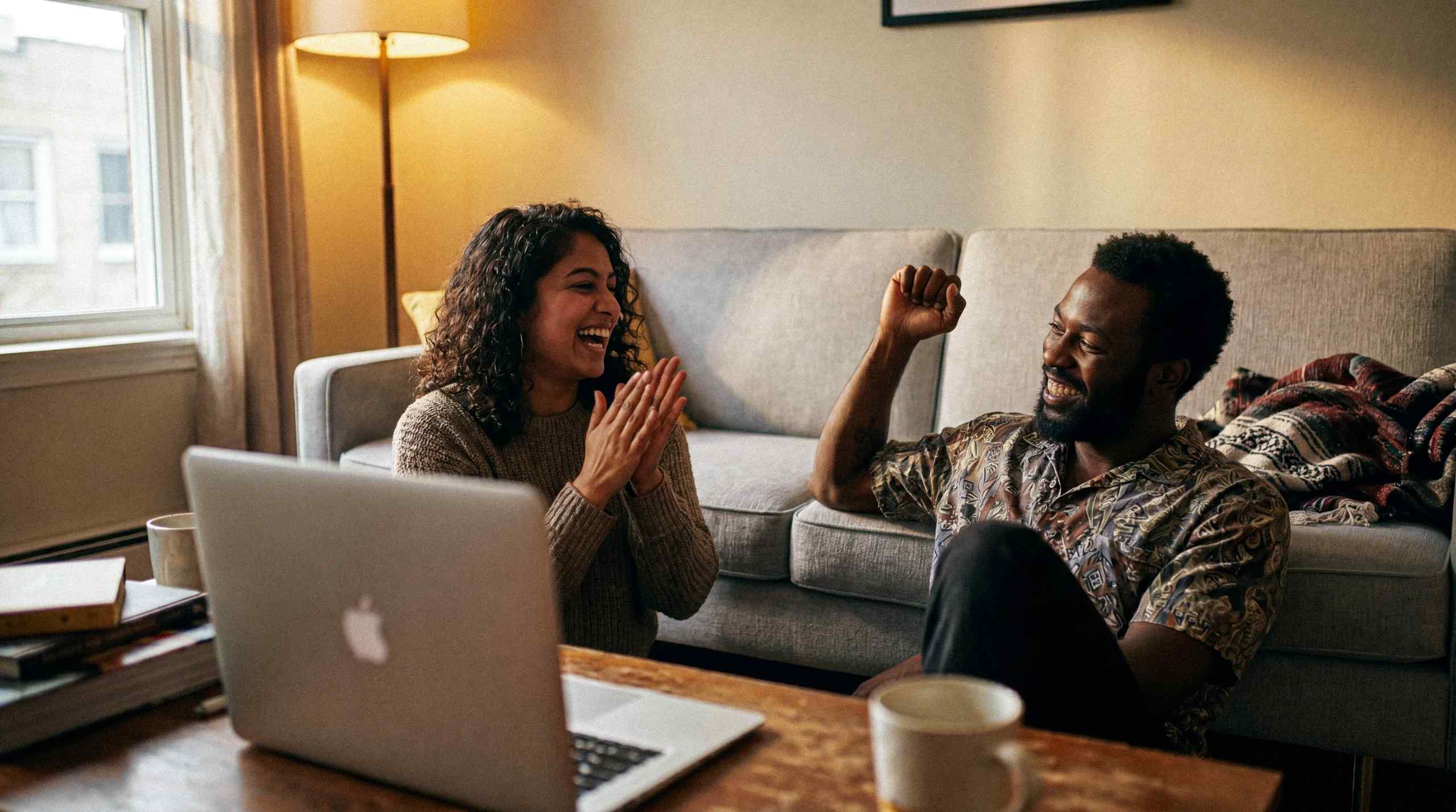 Two people sitting in a living room with a laptop on a coffee table